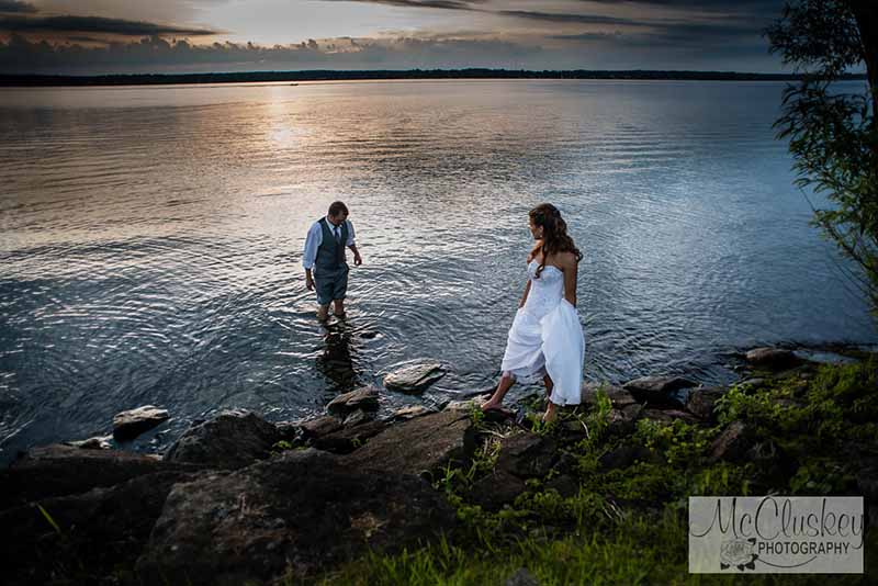 Bride and groom standing in the water by McCluskey Photography