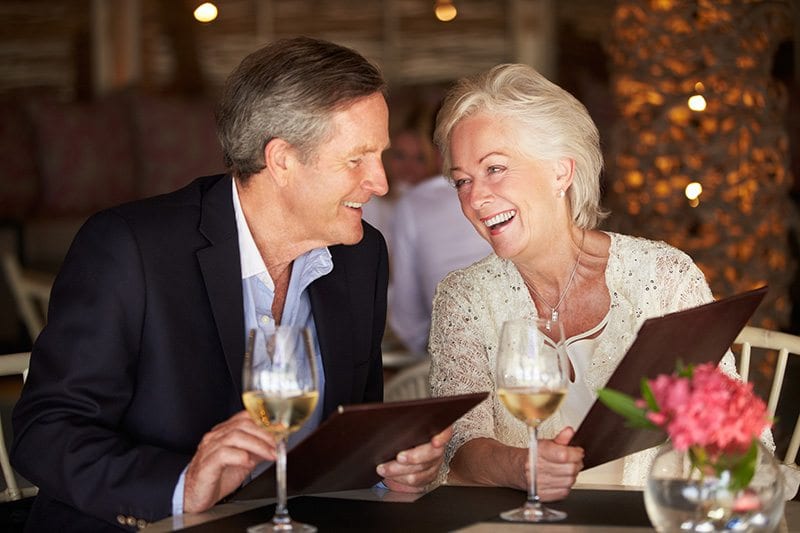 Elderly couple smiling and looking at dining menus